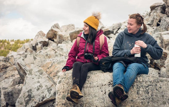 Two hikers take a break on top of a boulder field.