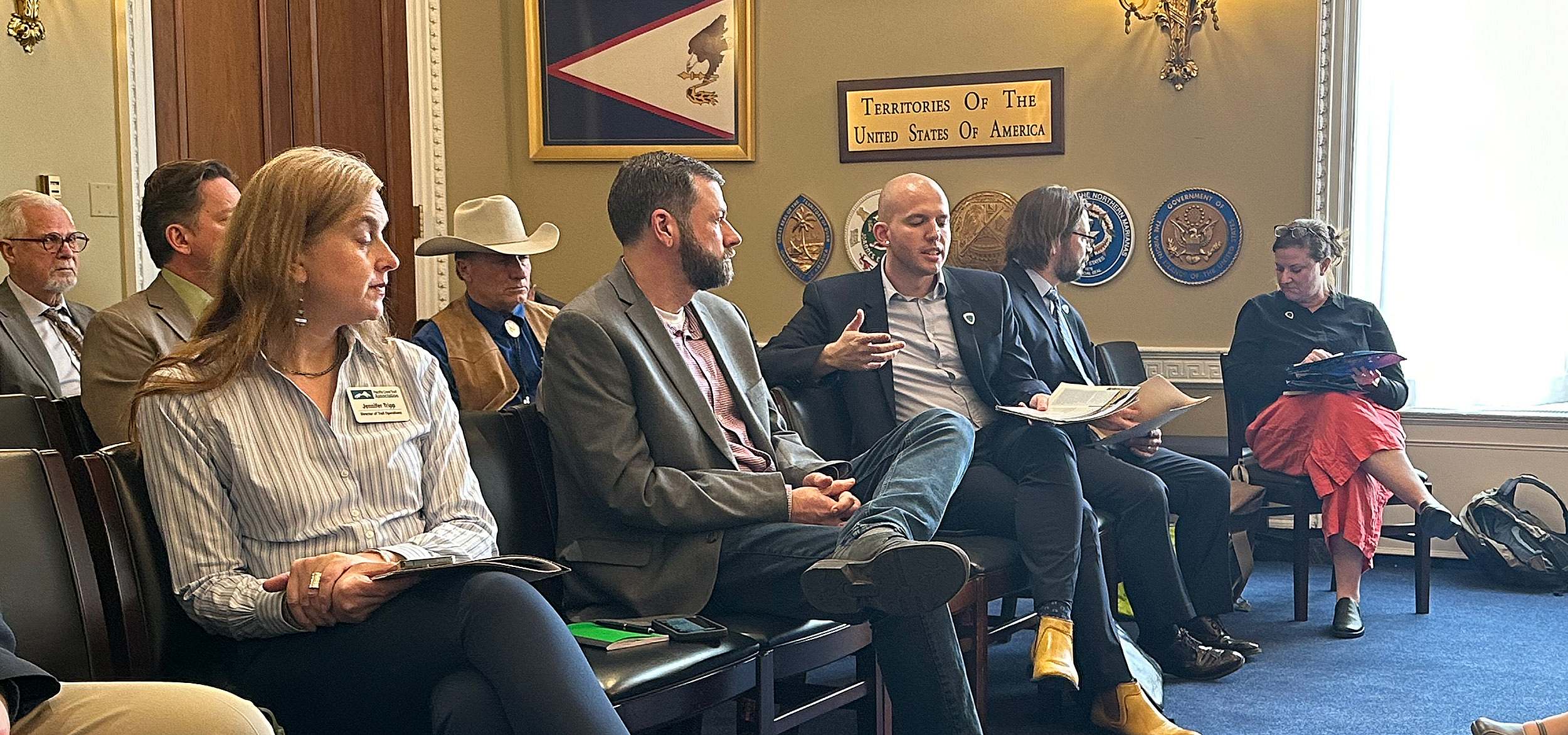 A group of people in business attire sit in two rows in a congressional committee room.