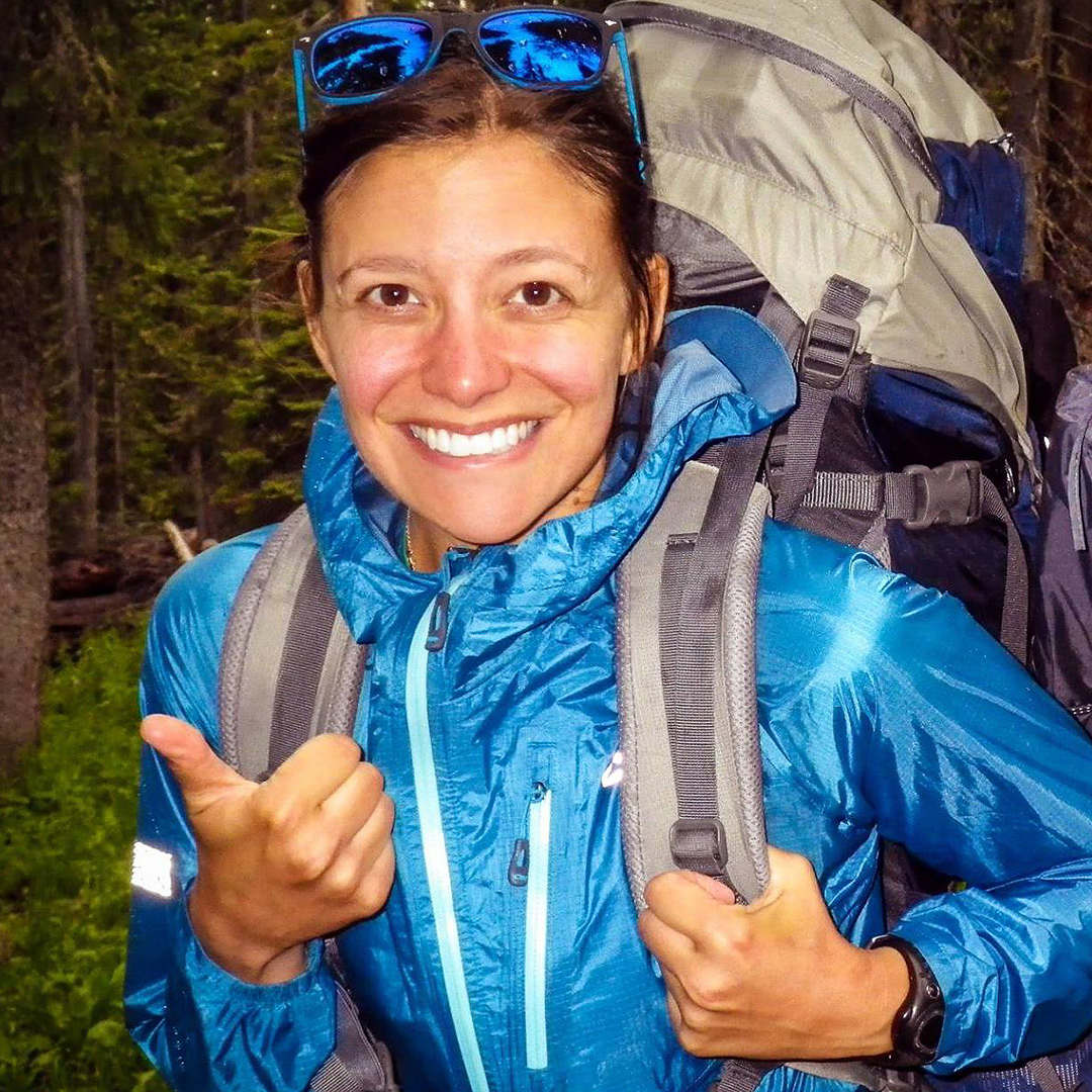Heather Distad gives a thumbs up while backpacking