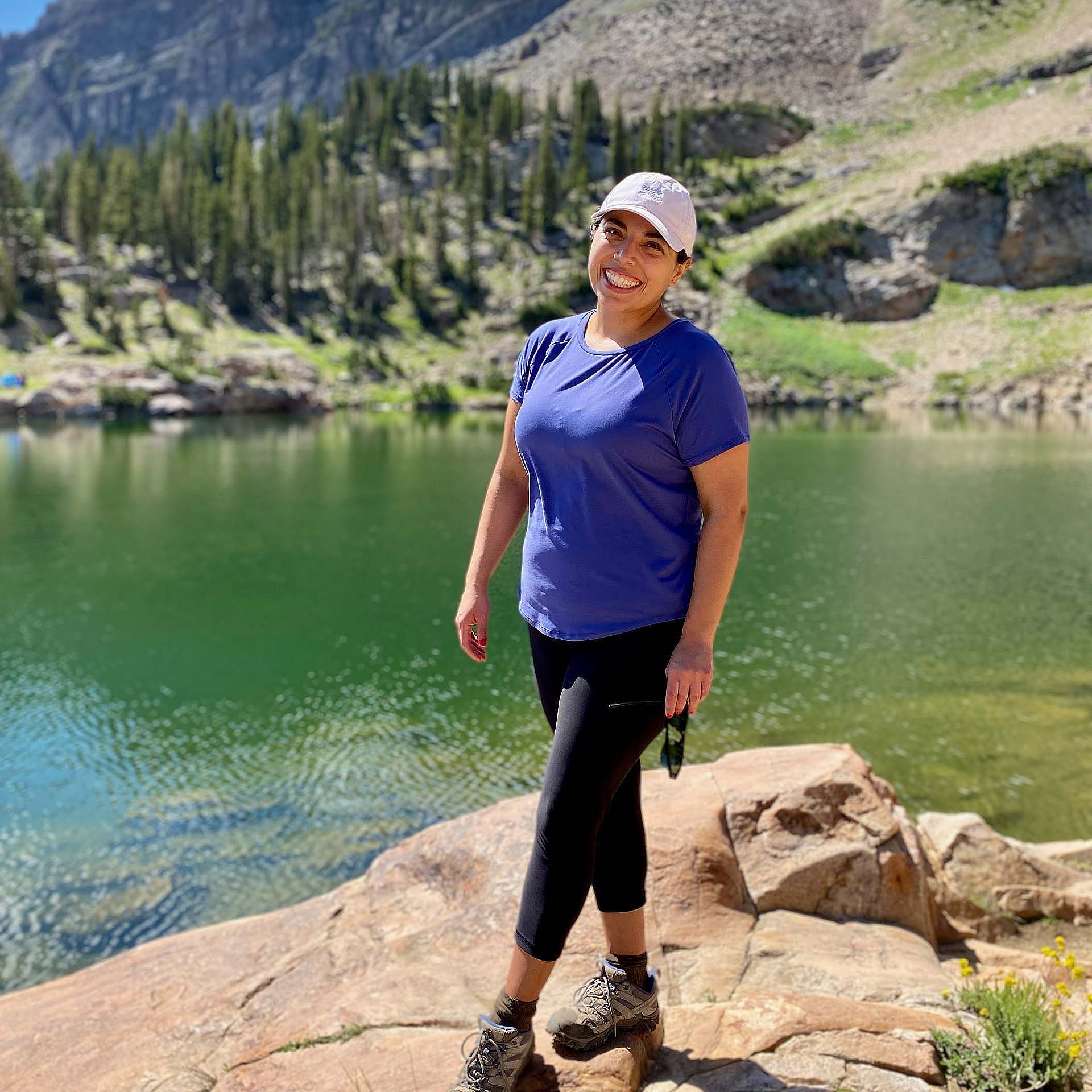 A hiker stands in front of an alpine lake.
