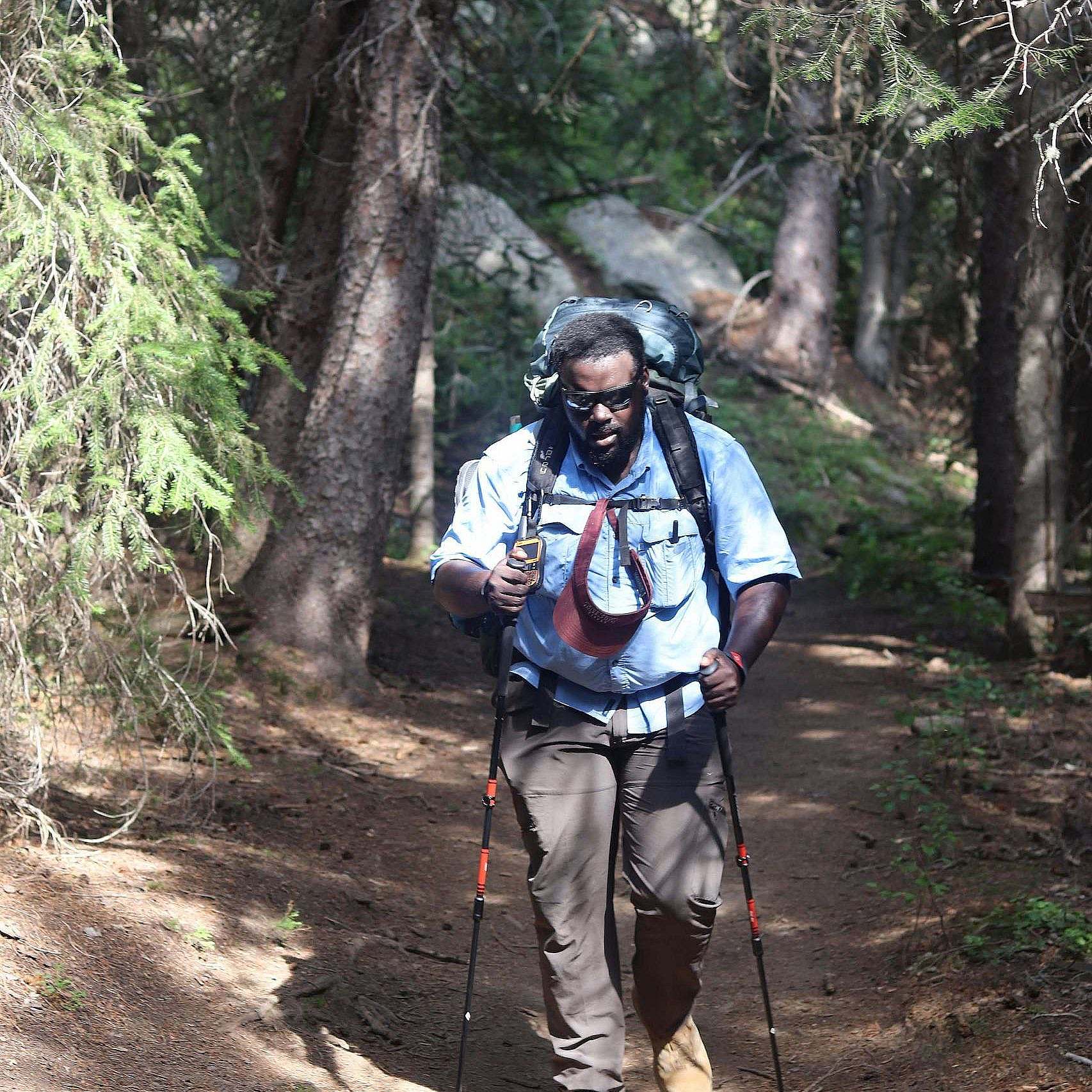 A backpacker hikes on a trail in a forest.